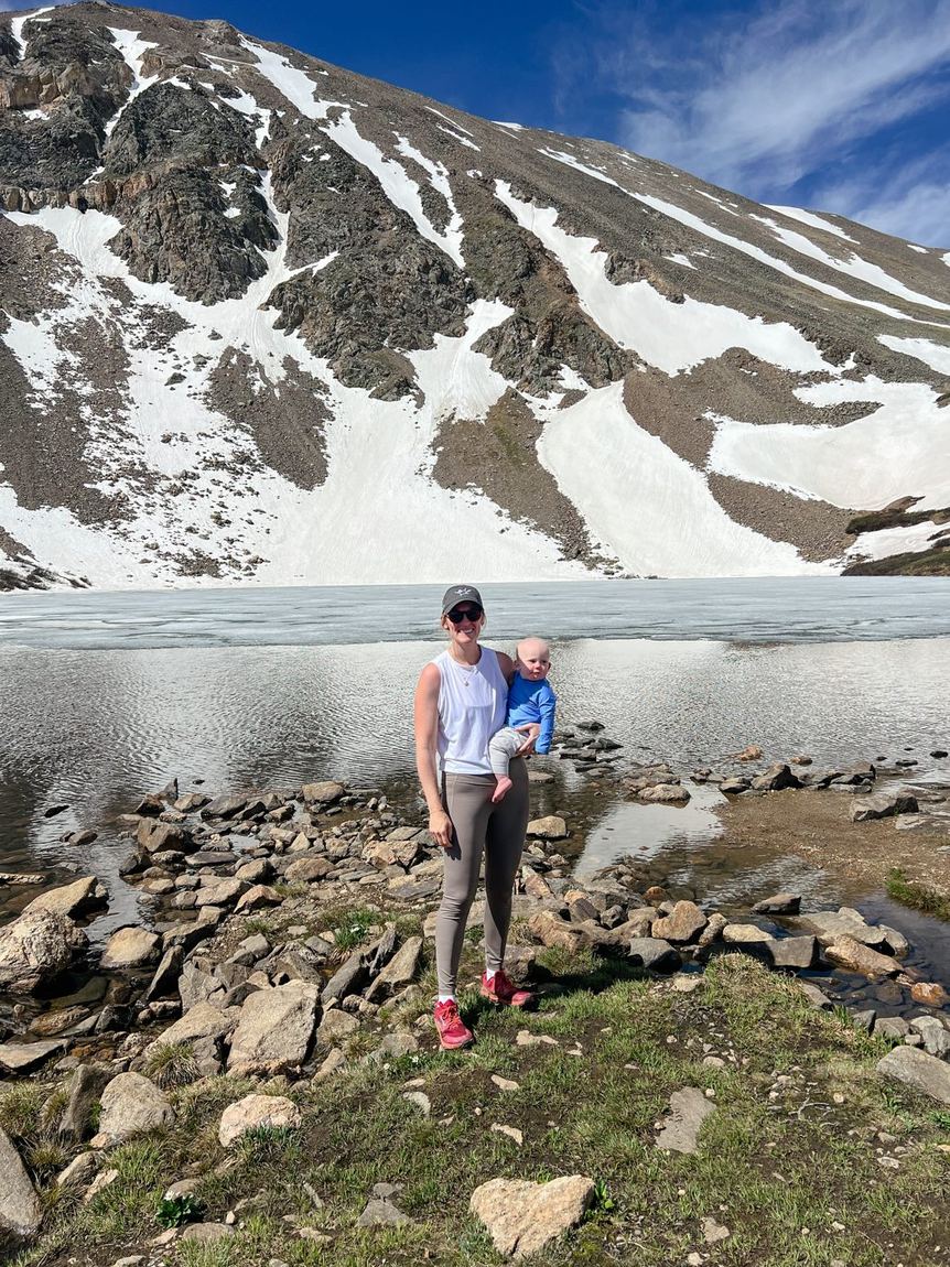 Christi hiking to an alpine lake with her son on her back