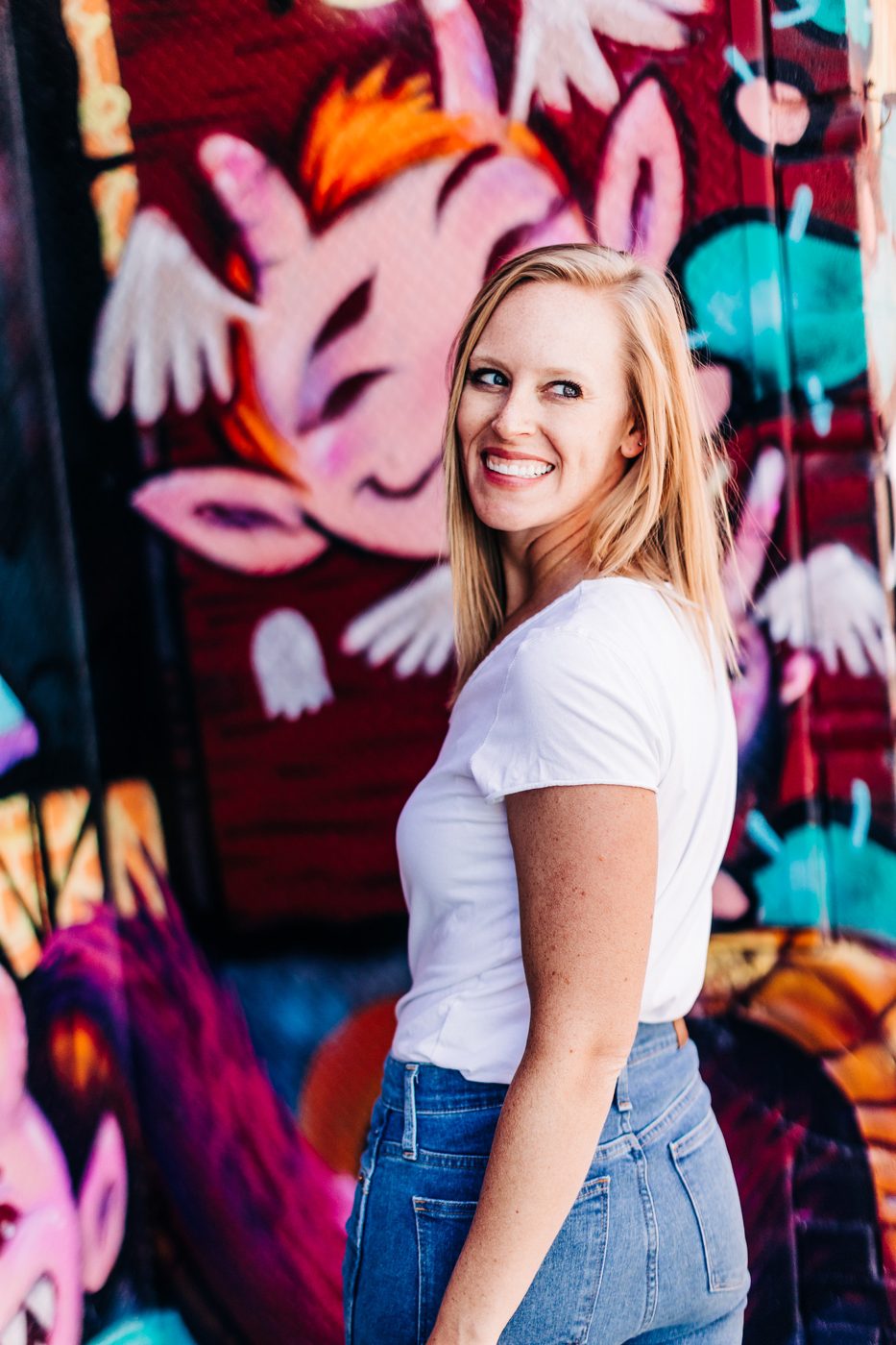 Christi Loucks in a white tee in front of a painted mural